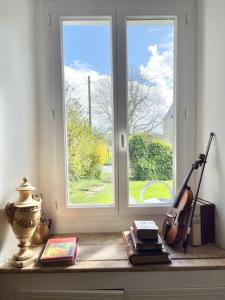 a room with a window and a violin and books at Maison bucolique champs de blé in Villers-Agron-Aiguizy
