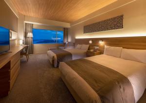 a hotel room with two beds and a flat screen tv at Setouchi Kojima Hotel Kurashiki in Kurashiki