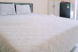 ein großes weißes Bett mit weißer Bettwäsche und Kissen in der Unterkunft RedLiving Apartemen kemang View - My Room LapanLapan Tower Mahagoni in Pekayon Satu + 15 Fotos