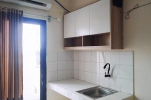 eine kleine Küche mit Spüle und Fenster in der Unterkunft RedLiving Apartemen kemang View - My Room LapanLapan Tower Mahagoni in Pekayon Satu