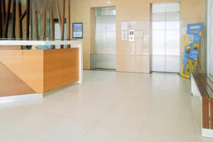 ein Flur mit weißen Fliesenböden und Glastüren in der Unterkunft RedLiving Apartemen kemang View - My Room LapanLapan Tower Mahagoni in Pekayon Satu