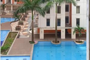 einen Luftblick auf einen Hotelpool mit Palmen in der Unterkunft RedLiving Apartemen kemang View - My Room LapanLapan Tower Mahagoni in Pekayon Satu