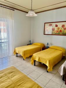 due letti in una stanza con lenzuola gialle di YELLOW HOUSE a Cefalù
