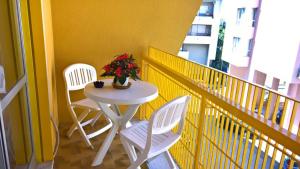 2 sedie e un tavolo con un vaso di fiori sul balcone di YELLOW HOUSE a Cefalù