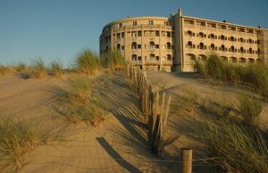 a building in the middle of a desert with tall grass at Caravan Aan Zee Arnani in Middelkerke