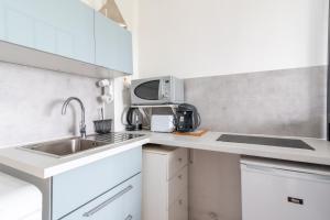 eine weiße Küche mit Spüle und Mikrowelle in der Unterkunft Le Ptit Henri - Studio à 20min de Paris in LʼHay-les-Roses