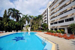 a large swimming pool with chairs and a building at Maeyom Palace Hotel in Phrae