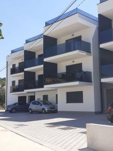 deux voitures garées sur un parking devant un immeuble dans l'établissement Apartman Filip, à Poljica