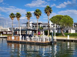 a dock with tables and chairs on the water with palm trees at Le Spinaker in Le Grau-du-Roi