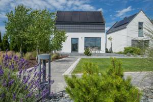 a white house with a black roof at BalticTime - wanna spa 24h & sauny w cenie in Ostrowo