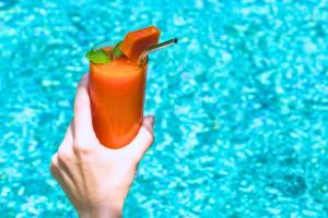 a hand holding a orange cocktail with a drink at Liam 1 BR Bamboo Private Pool Villa JU63 in Seminyak
