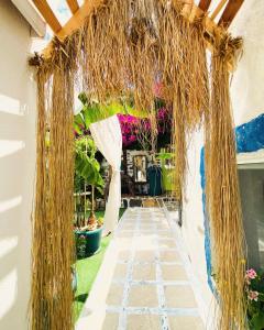 a walkway in a garden with a thatch roof at Badehan Guest House in Cesme