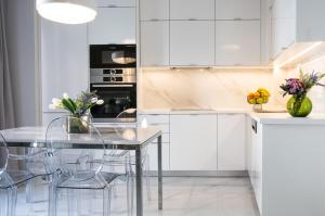 a kitchen with white cabinets and a glass table at Oikos luxury central apartment in Agios Nikolaos