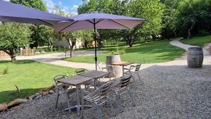 a table and chairs with an umbrella in a park at Gîte l'Enclos Ô rendez-vous Roquefeuil-Pays de sault- avec jardin in Roquefeuil