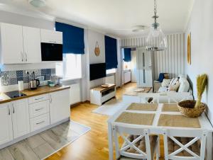 kuchnia i salon z białymi szafkami i stołem w obiekcie Apartament Łazienna River View AC Progres w Toruniu