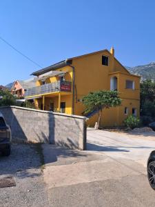 a yellow house with a fence in front of it at Apartments Mara Bela in Karlobag