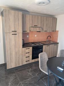 a kitchen with wooden cabinets and a table with chairs at Apartments Mara Bela in Karlobag