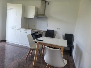 eine Küche mit einem weißen Tisch und Stühlen in der Unterkunft Monteurwohnungen Distelfeld in Saarbrücken