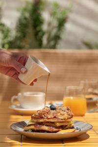 a person pouring syrup onto a stack of pancakes at Astikon House in Athens