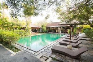 a swimming pool with lounge chairs next to a house at Aqua Bali Villa in Canggu