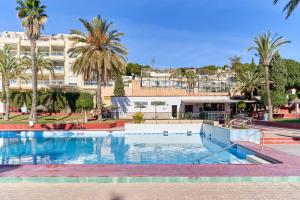 a swimming pool with palm trees and a building at Apartamento Casita del Mar in La Herradura