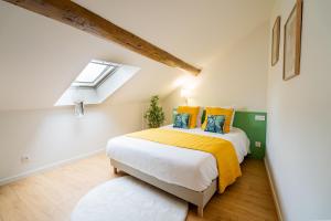 a bedroom with a bed with a yellow blanket and a window at Au Duplex d'Or Centre Historique in Besançon +22 photos