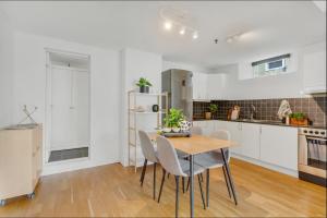 cocina blanca con mesa de madera y sillas en 2-Bedroom Apartment with Private Entrance Near Tromsø City Centre, en Tromsø