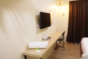 a hotel room with a desk with a tv on the wall at No.31 Maple Inn in Simpang Ampat