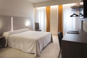 a hotel room with a bed and a desk at Alfa Fiera Hotel in Vicenza