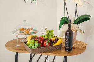 a basket of fruit on a table with a bottle of wine at La Loggia Suite in Marsala