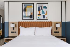 a bedroom with a large bed with two pictures on the wall at voco Belfast by IHG in Belfast