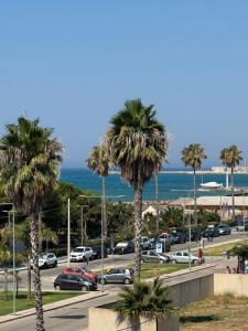 a parking lot with palm trees and the ocean at Andrea Doria Hotel in Marina di Ragusa