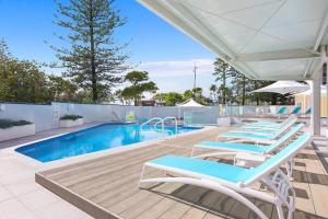 a row of lounge chairs next to a swimming pool at Peninsula Apartments managed by Gchs in Gold Coast