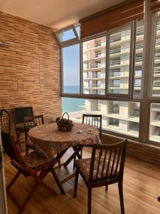 a dining room with a table and chairs and a large window at Amazing Magnolia in Batumi