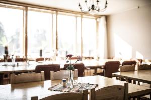 a dining room with tables and chairs and windows at Hotell Nederhögen Vildmarkscenter in Rätan