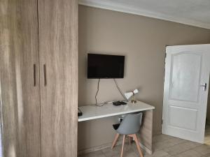 a room with a desk with a monitor and a chair at AndriMat Roadside Guest Lodge in Mogwase