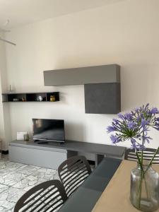 una sala da pranzo con un tavolo e sedie e un vaso con fiori viola di Vista Mare a 150 mt dalla spiaggia - free parking e AC a Pietra Ligure