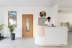 a man is sitting at a desk in a room at The Lodgers Studio Apartment Near Mall FiftyOne Gurugram in Gurgaon