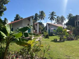 タマンダレーにあるCAJUEIROS - Chales Aconchegantes a 2 Minutos da Praiaのヤシの木のある家と庭