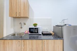 a kitchen with a counter with a microwave and a refrigerator at The Lodgers Studio Apartment Near Mall FiftyOne Gurugram in Gurgaon