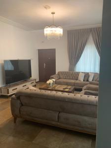 a living room with a couch and a flat screen tv at Beige Villa at East Legon ANC in Accra