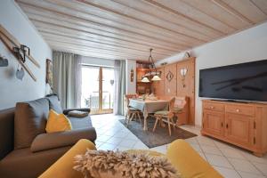 a living room with a couch and a tv and a table at Ferienwohnung Alpina in Roßhaupten