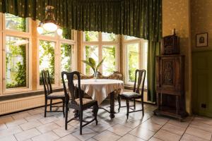 a dining room with a table and chairs and windows at Villa Irena in Sopot