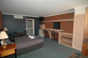 a room with a bed and a kitchen with a brick wall at Poachers Paradise in Rutherglen