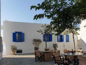 a white building with blue windows and tables and chairs at StathisApart1 in Amorgos