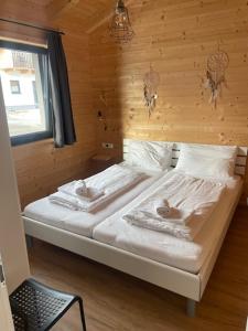a bed in a room with a wooden wall at Bungalow Rattendorf - bij skigebied Nassfeld in Hermagor