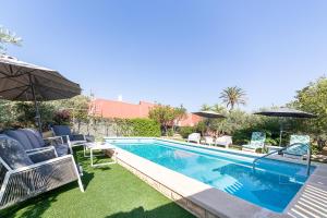 a swimming pool with chairs and umbrellas in a yard at Cortijo Indalo in Pechina