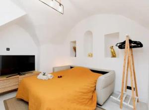 un soggiorno con una coperta gialla e una televisione di Maison en centre de Cannes - Le Suquet a Cannes