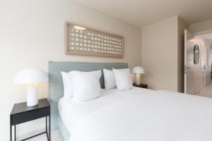 Un dormitorio con una gran cama blanca con almohadas blancas. en Kaaiman Ostend - Casselbergh Residences, en Ostende