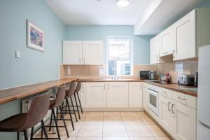 a kitchen with white cabinets and bar stools at Chamberlain House in Derry Londonderry